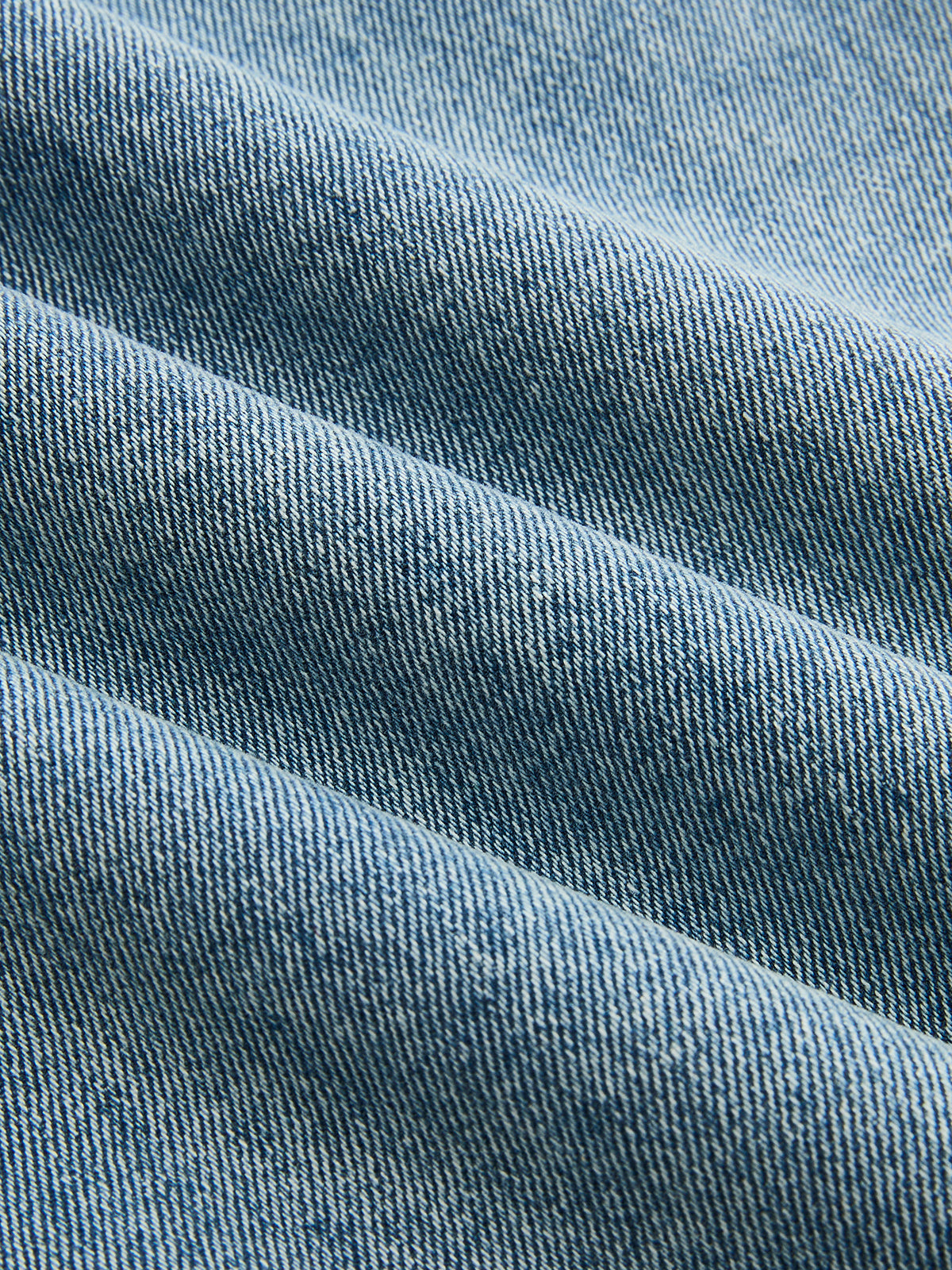 Light blue denim jeans with diagonal twill weave, soft folds, and subtle shaded details.