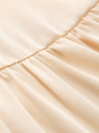Pleated light beige satin midi dress with smooth, shiny texture and ruched split detail.