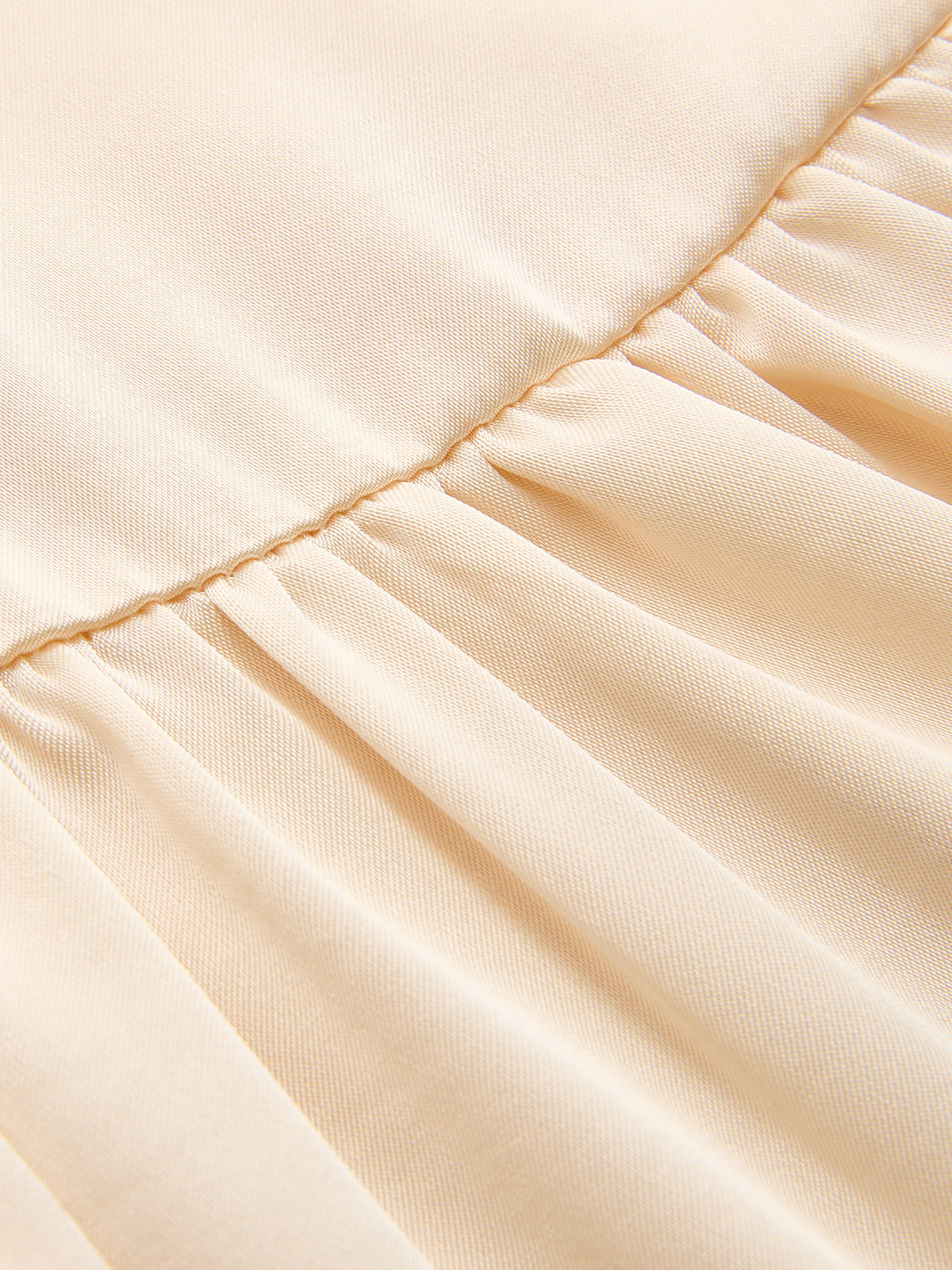 Pleated light beige satin midi dress with smooth, shiny texture and ruched split detail.
