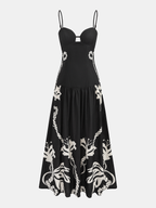A black slim-fit maxi dress with thin straps and white floral patterns at the hem.