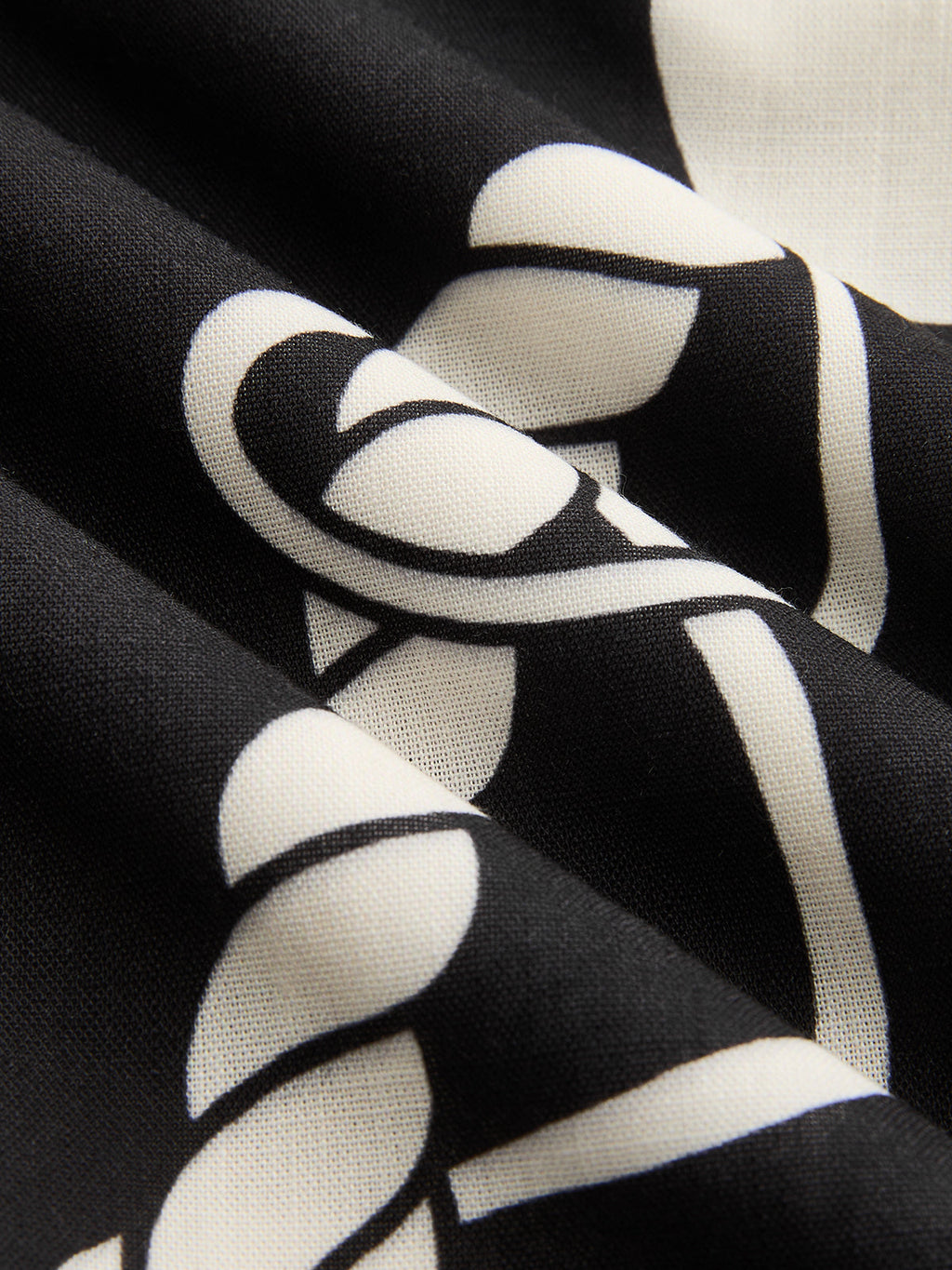 Black maxi dress with bold white abstract pattern, featuring soft folds and smooth texture.