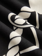 Black maxi dress with bold white abstract pattern, featuring soft folds and smooth texture.