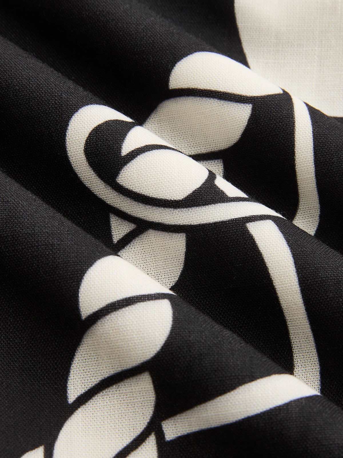 Black maxi dress with bold white abstract pattern, featuring soft folds and smooth texture.