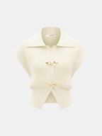 Cream knit vest with contrast trim, short sleeves, wide collar, and gold metal clasps.