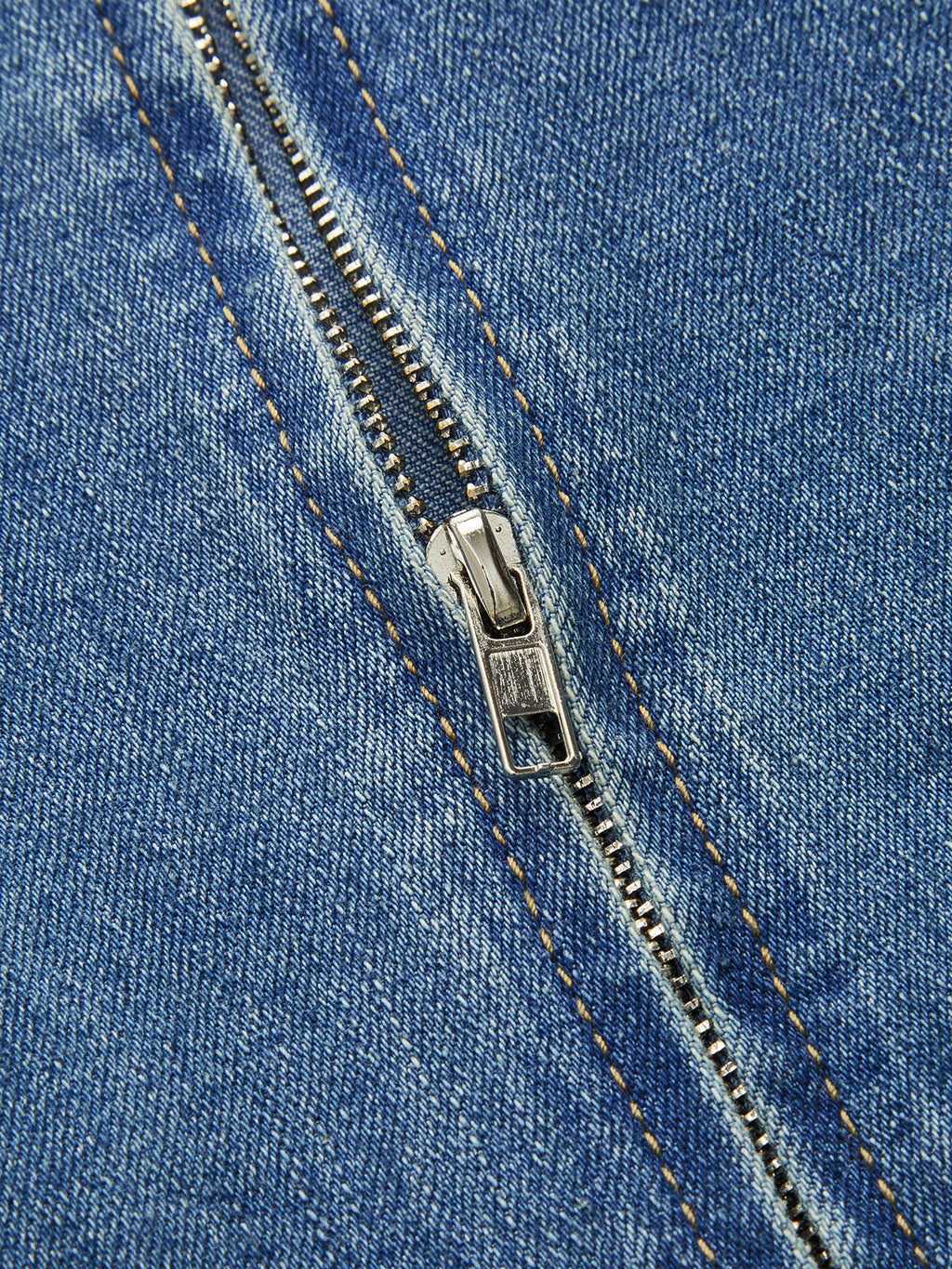 Close-up of a sleeveless denim midi dress with orange-stitched zipper, partially open teeth.
