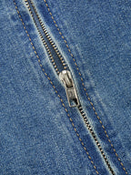 Close-up of a sleeveless denim midi dress with orange-stitched zipper, partially open teeth.