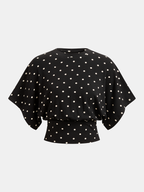 Wide-sleeved black batwing top with white polka dots, crew neck, and cinched waist.