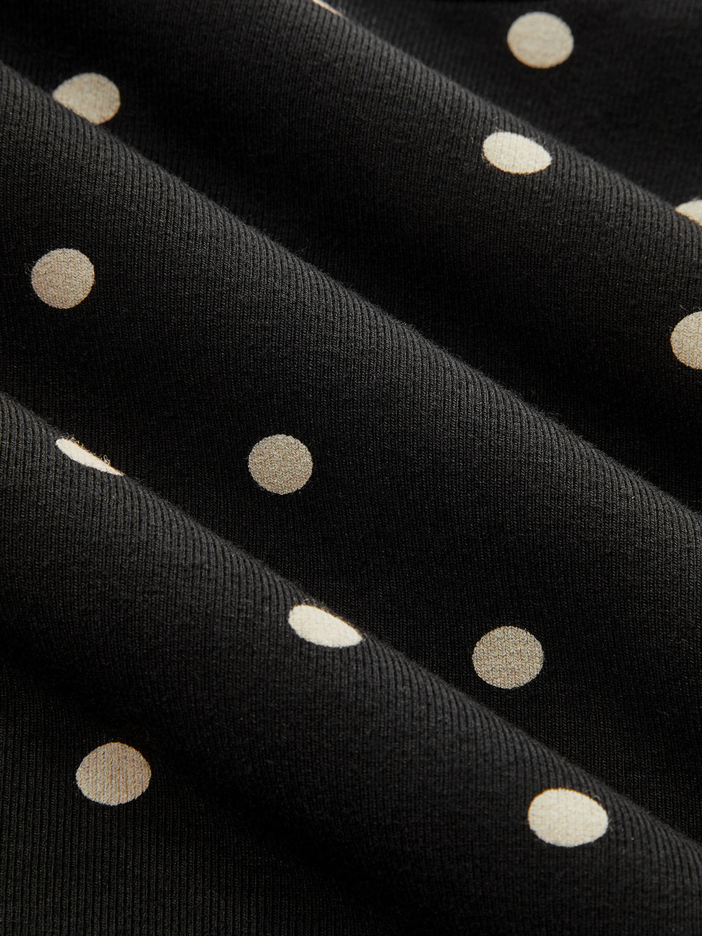 Black jersey batwing top with cream polka dots, cinched waist, and chic short sleeves.