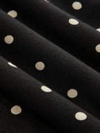 Black jersey batwing top with cream polka dots, cinched waist, and chic short sleeves.