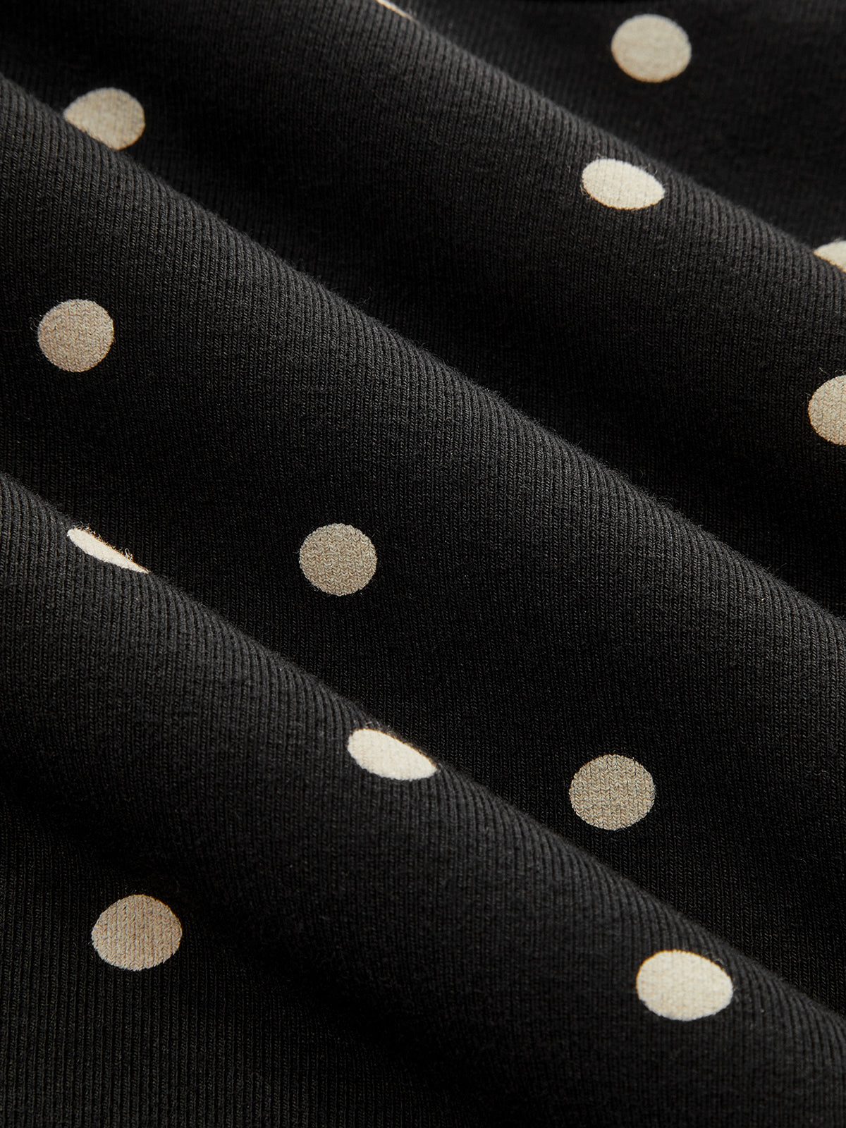 Black jersey batwing top with cream polka dots, cinched waist, and chic short sleeves.