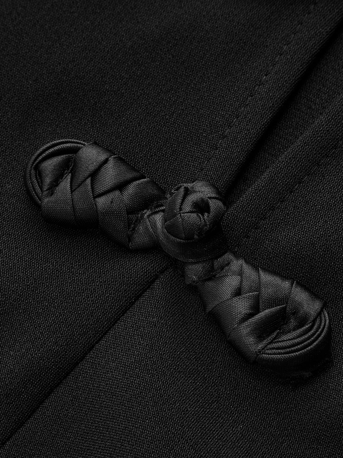 Close-up of a Mandarin collar dress featuring intricate black frog button knots on smooth fabric.