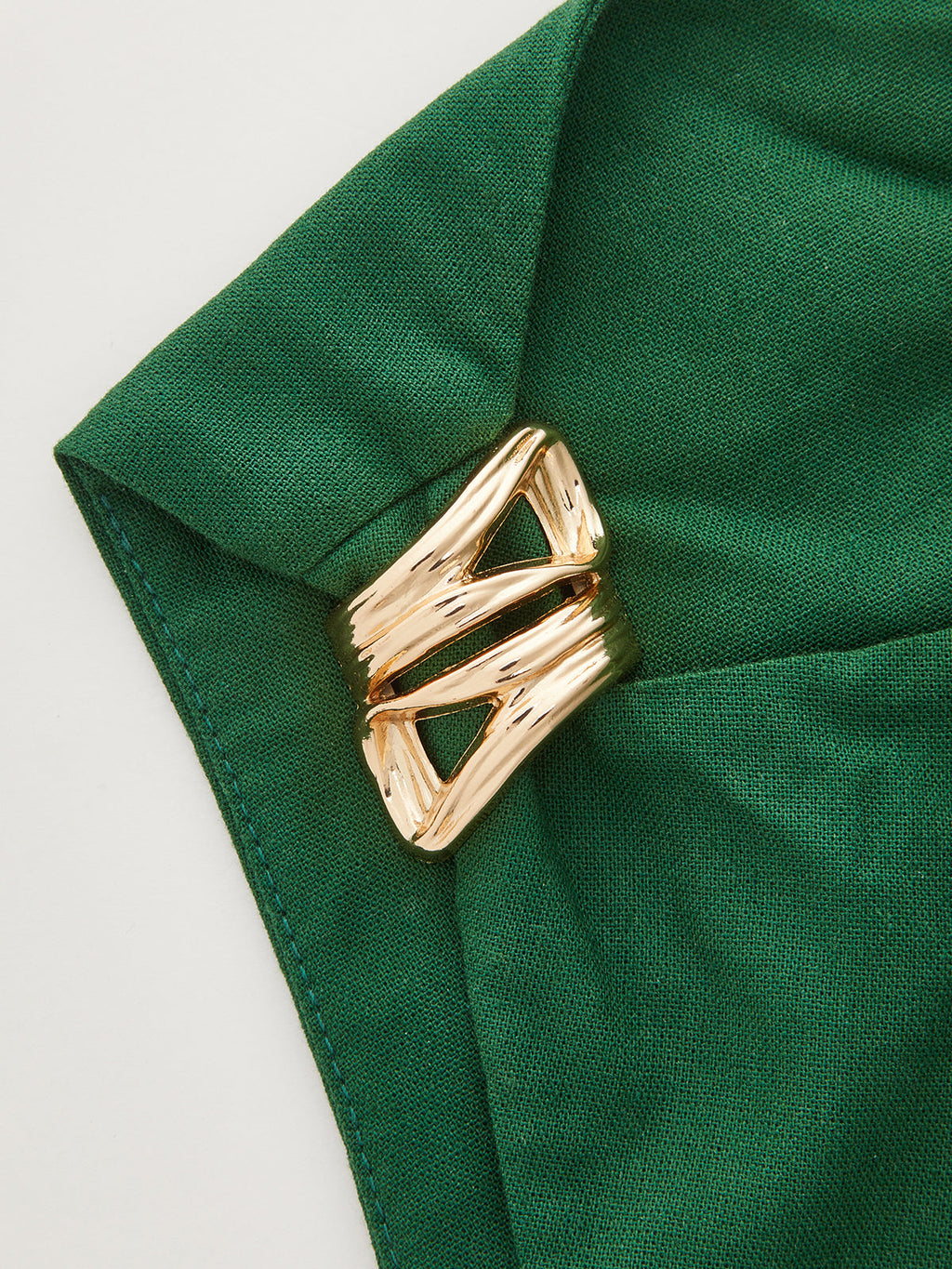 One-shoulder linen blend mini dress with ruching, secured by a shiny gold brooch.