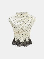 A sleeveless top with black polka dots, lace hem, and gentle ruching at the waist.