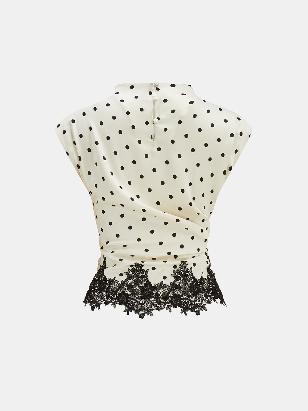 Cream polka dot sleeveless top with ruched waist, lace hem, and buttoned neck closure.