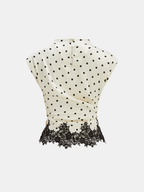 Cream polka dot sleeveless top with ruched waist, lace hem, and buttoned neck closure.
