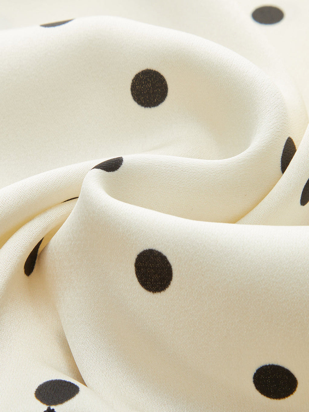 Soft cream sleeveless top with black polka dots, ruching, and a lace-trimmed hem.