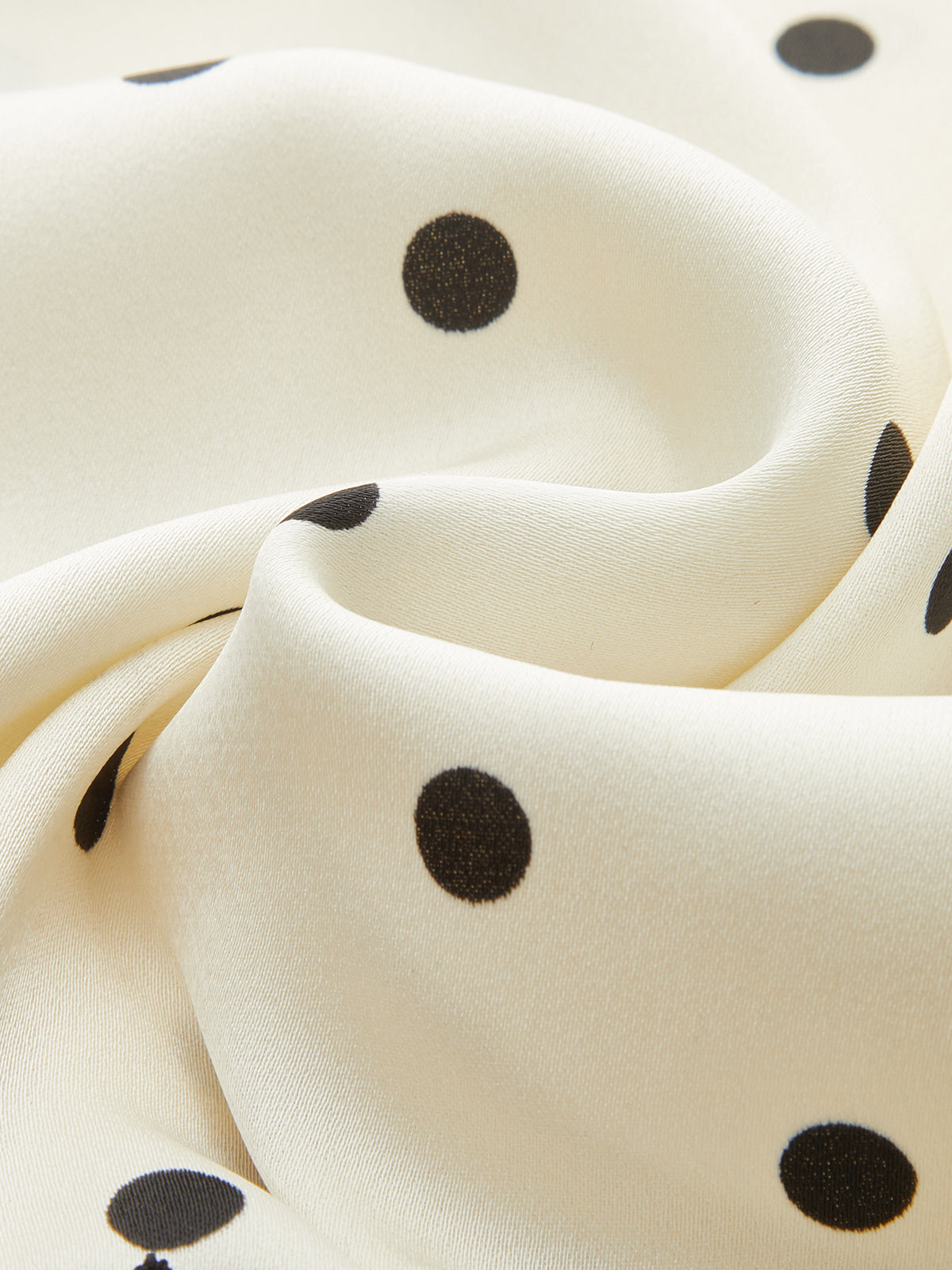 Soft cream sleeveless top with black polka dots, ruching, and a lace-trimmed hem.