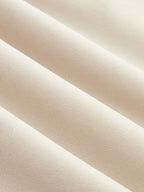 Light beige, ribbed fabric romper with smooth texture and parallel ridges in close-up.