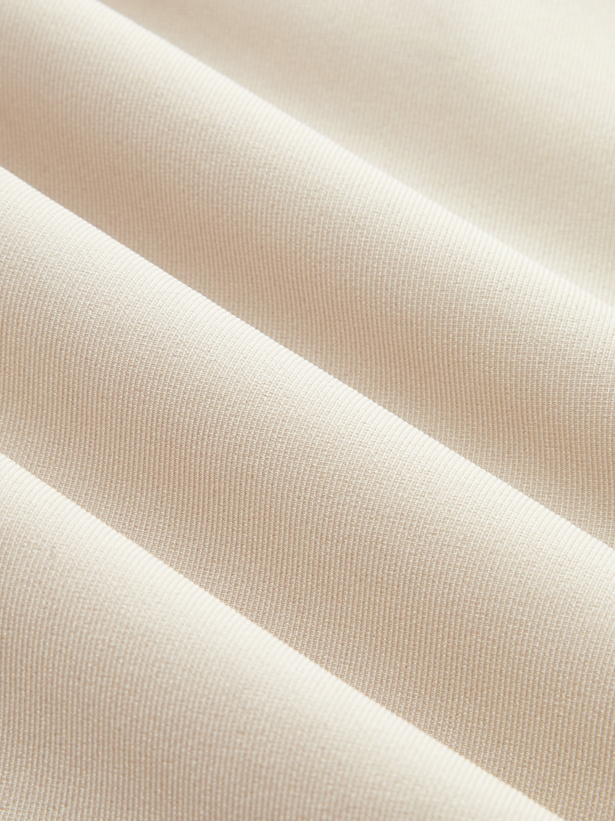 Light beige, ribbed fabric romper with smooth texture and parallel ridges in close-up.