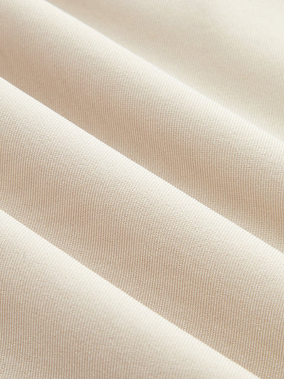 Light beige, ribbed fabric romper with smooth texture and parallel ridges in close-up.