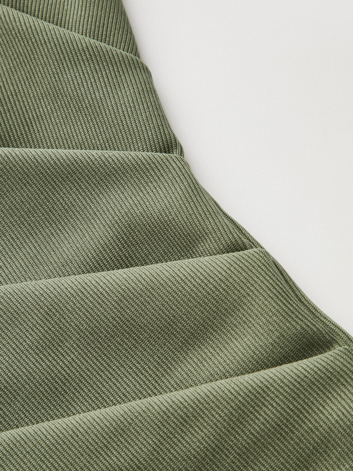 Olive green ribbed mock neck top with short sleeves, ruching, and diagonal textured seams.