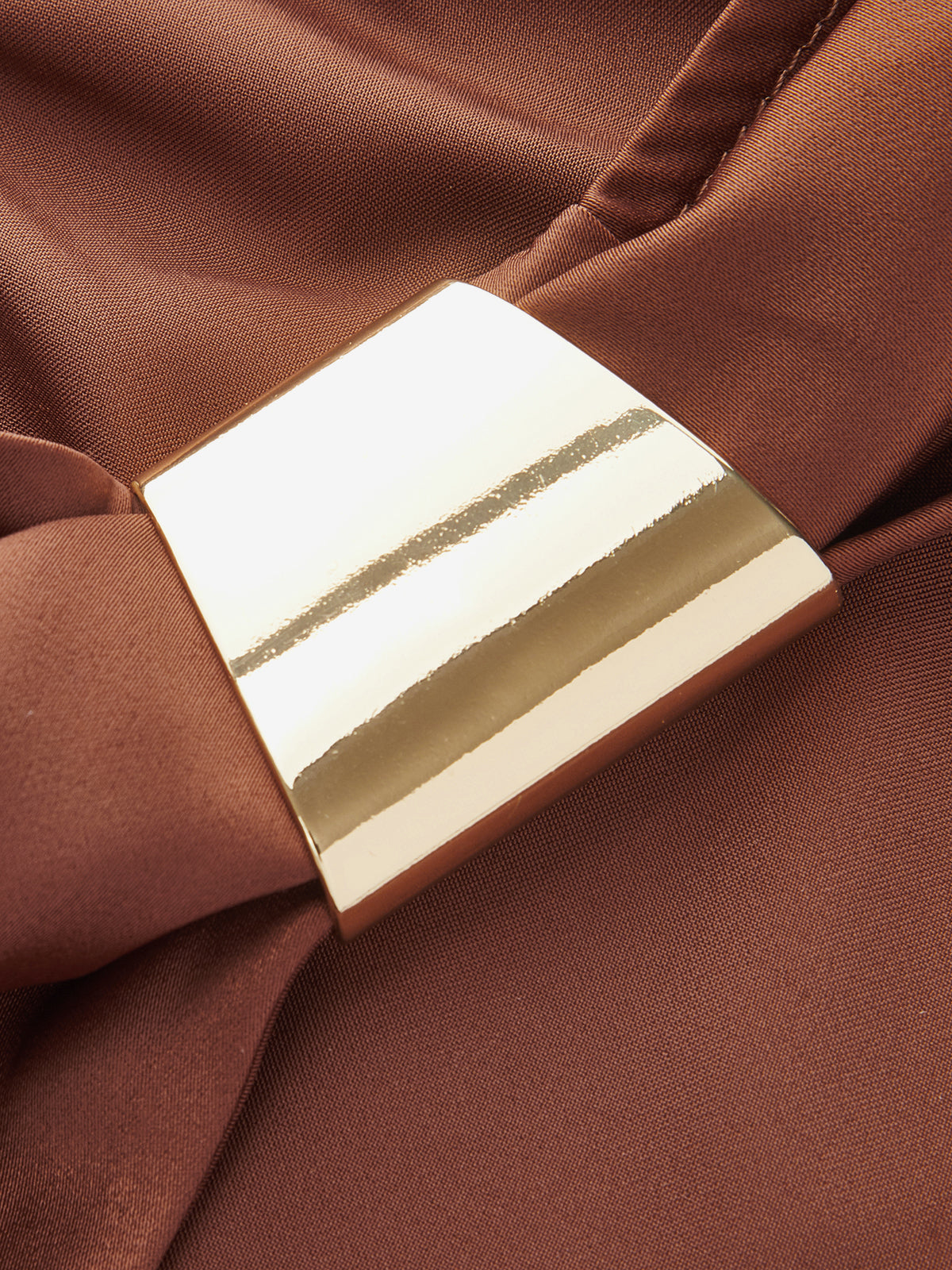 Sleeveless cowl neck satin cocktail dress with gold rectangular buckle and smooth brown fabric.