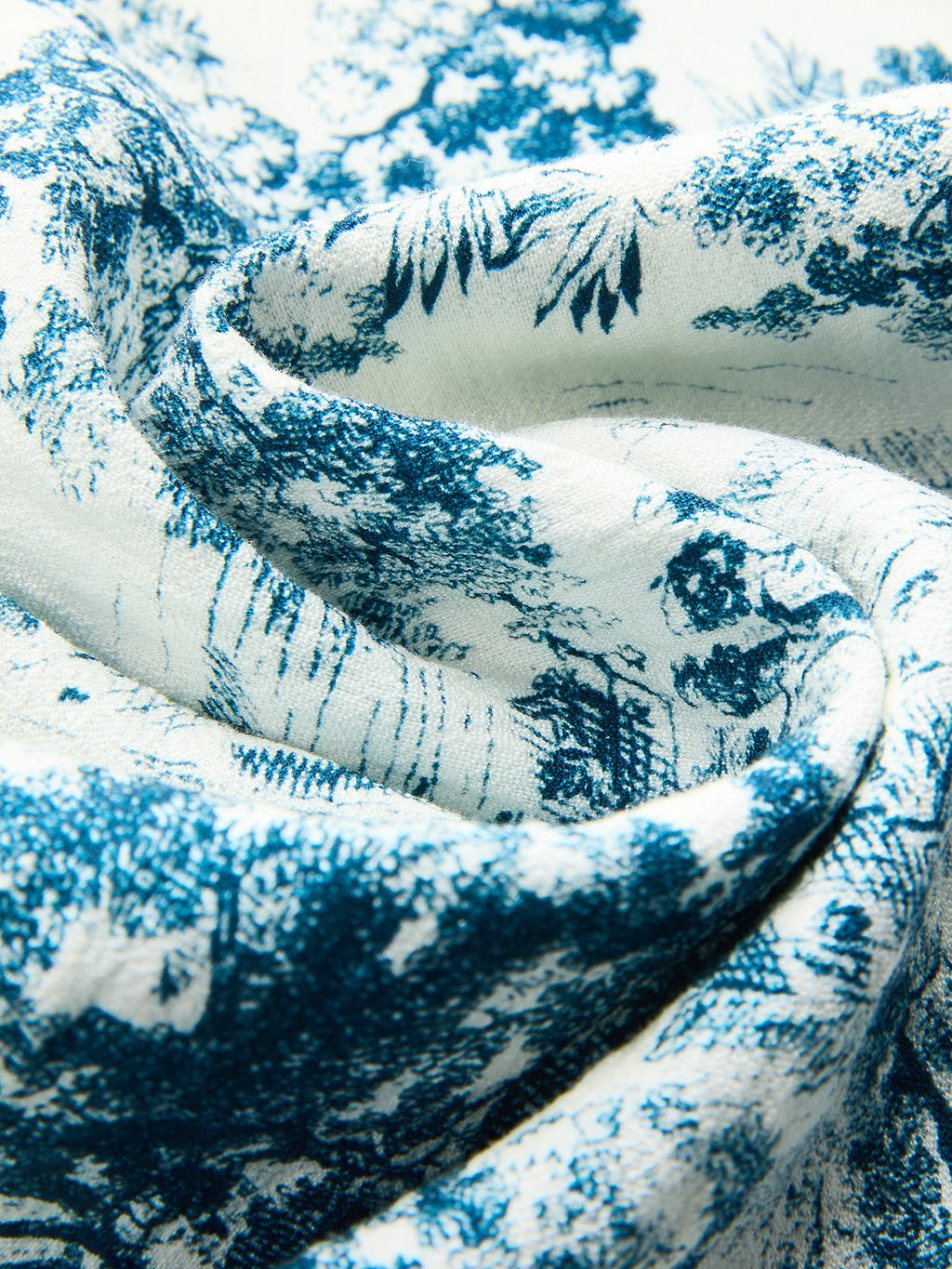 White fabric knotted crop top with blue toile pattern, delicately folded to show intricate design.