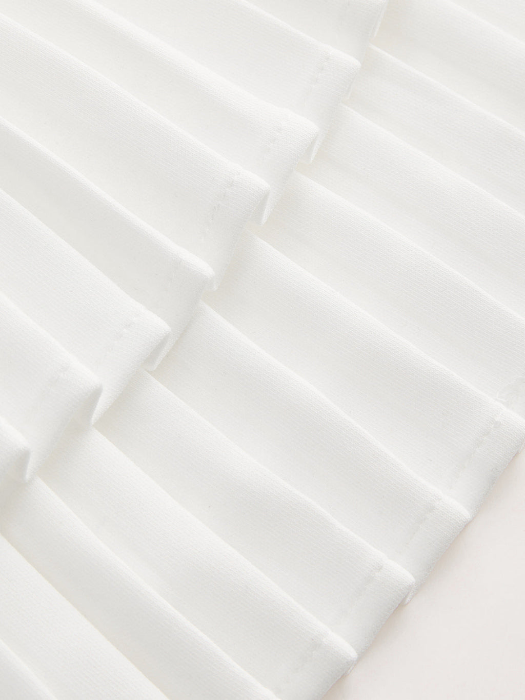 White pleated dress with crisp geometric texture and soft shadows, creating a modern look.
