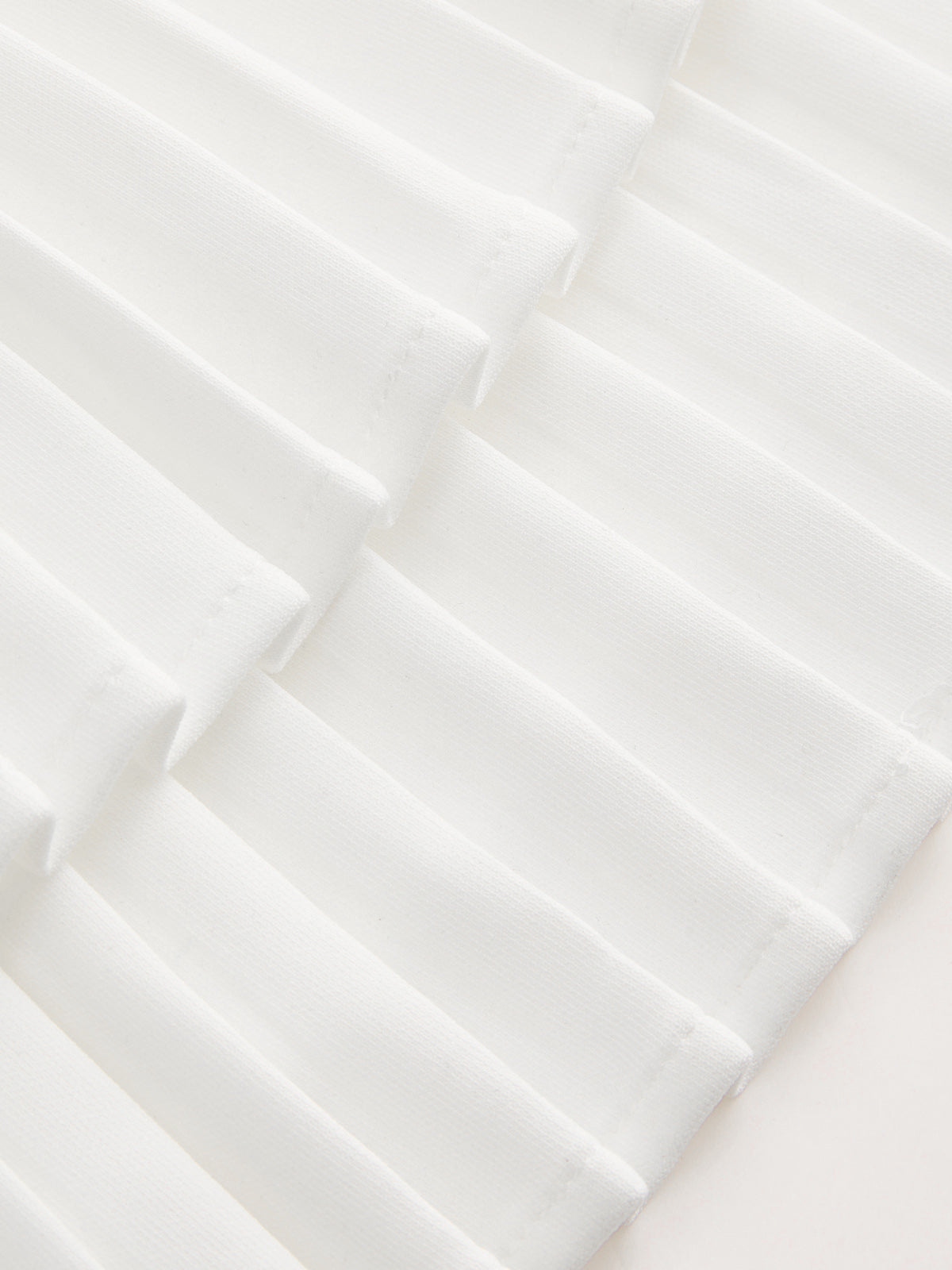 White pleated dress with crisp geometric texture and soft shadows, creating a modern look.