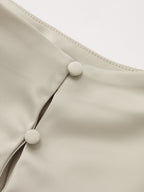 Asymmetrical satin blouse with draped ruching, cream stand collar, and two covered buttons.