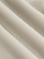 Asymmetrical satin blouse in light beige with draped ruching and elegant diagonal folds.