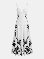 Sleeveless white camisole dress with slim straps and bold black floral vine lower pattern.