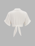 Short-sleeved, collared white knotted crop top with tie-back and coordinated patterned pants.