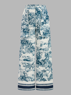 Wide-leg, high-waisted blue and white toile pants with front pleats and a fabric belt.