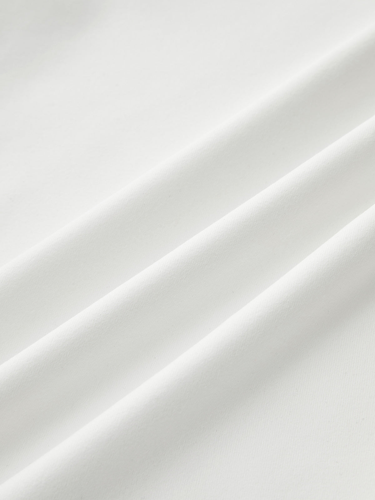 Mock neck sleeveless top in smooth white fabric with ruched detail and soft diagonal folds.