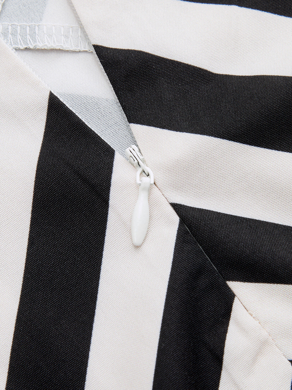 Close-up of a white zipper with oval pull tab on black and white striped maxi dress.
