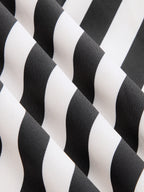 Black and white diagonal striped halter maxi dress with wavy fabric folds and backless design.