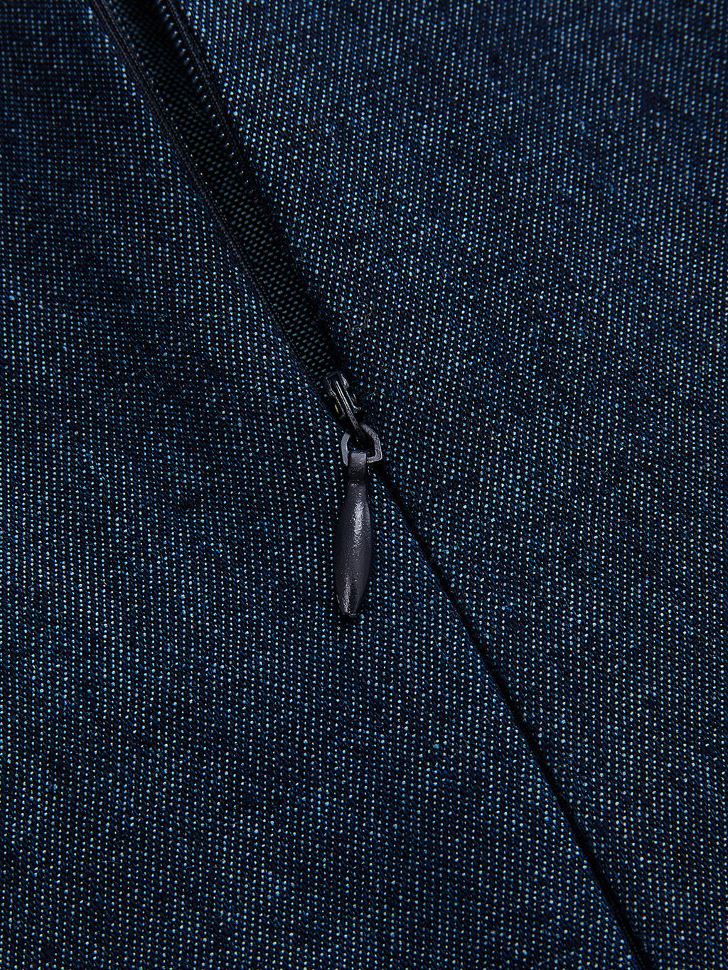 Close-up of a partially unzipped black zipper on a dark blue, speckled denim dress.