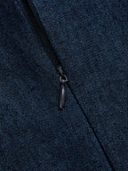 Close-up of a partially unzipped black zipper on a dark blue, speckled denim dress.