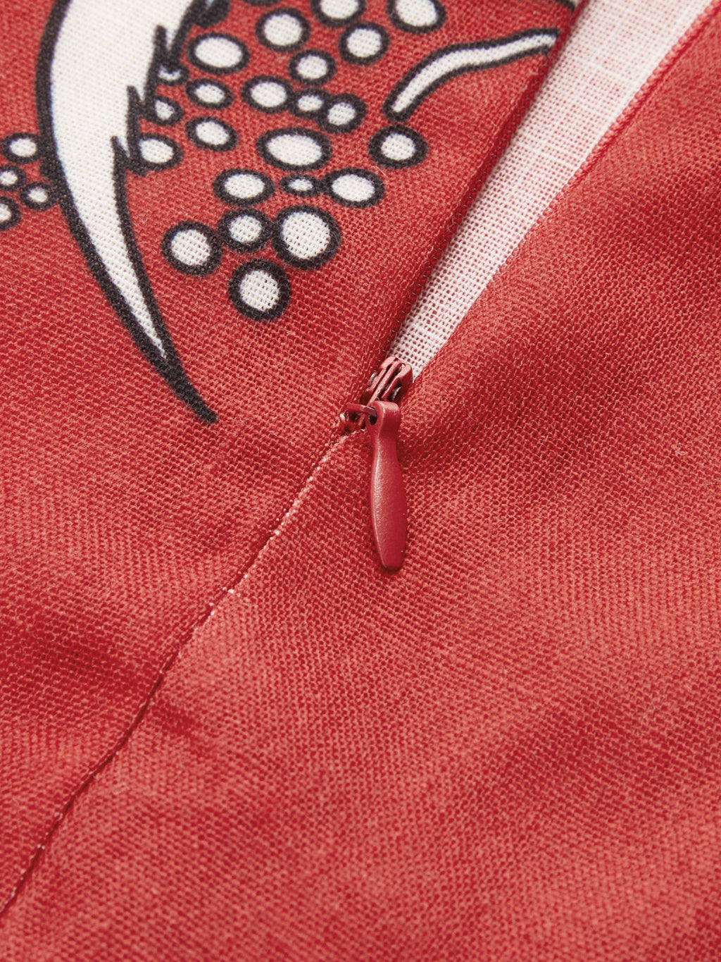 Red zipper detail on a red cami dress with white and black tropical print.