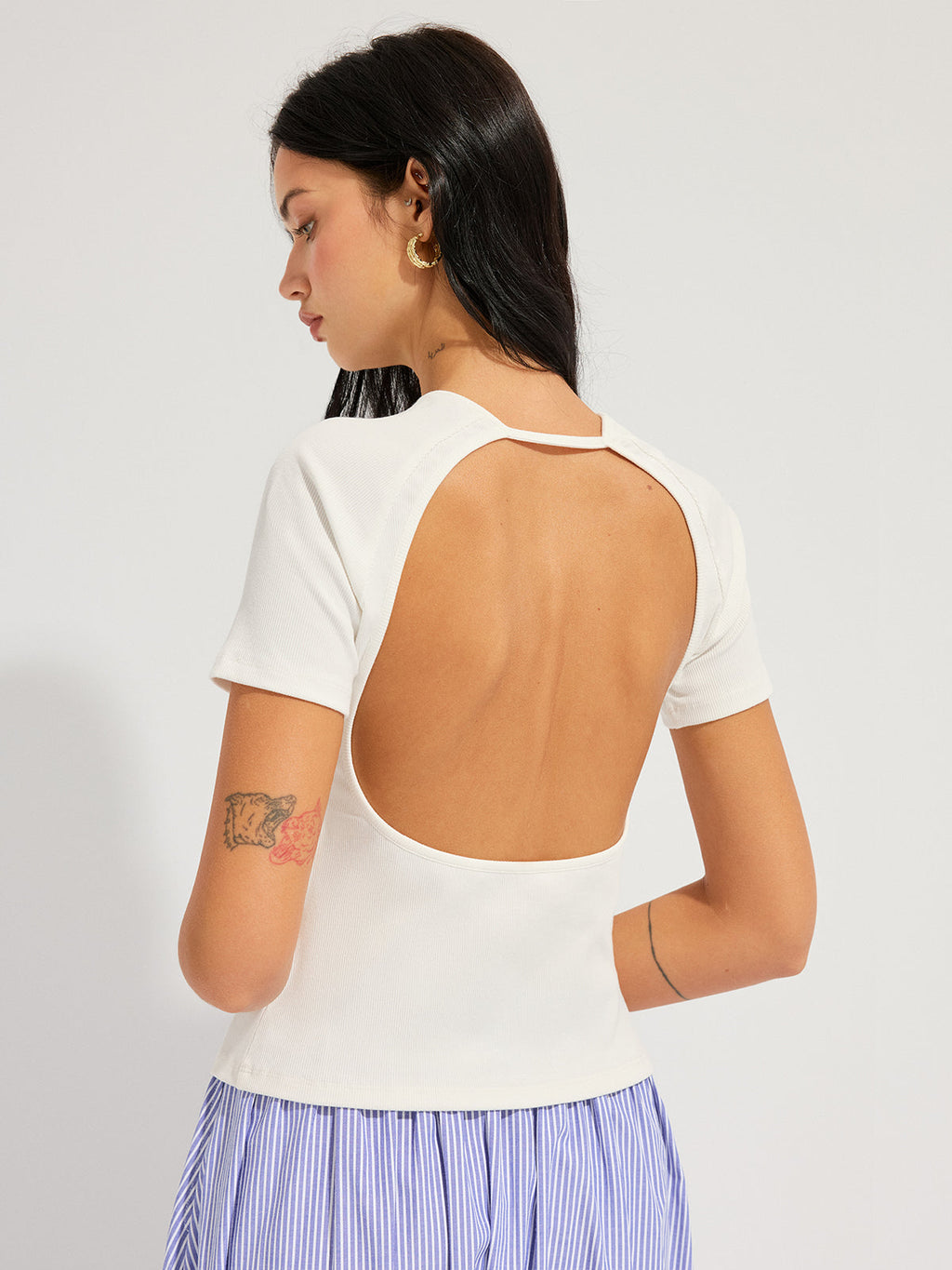 Open back ribbed top with short sleeves, paired with a blue and white striped skirt.