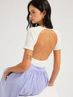 LA FINE FLEUR Open Back Ribbed Top with short sleeves and light blue striped skirt.