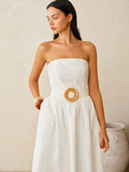 A white cotton linen strapless maxi dress with belt, featuring a flared skirt.