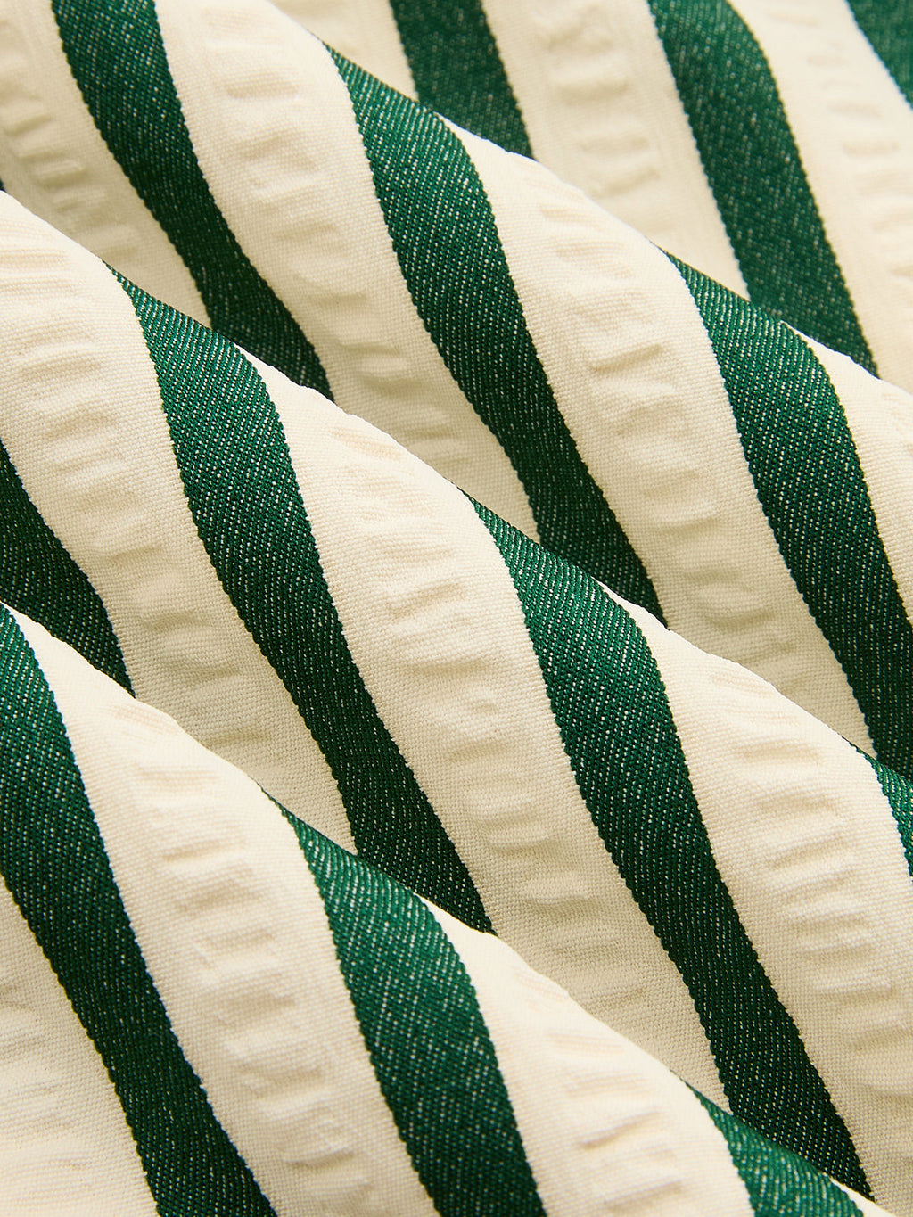Textured fabric of a striped sleeveless mini dress with diagonal green and off-white stripes.