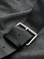 Sleeveless ruched dress with asymmetrical hem and a black belt with silver buckle.