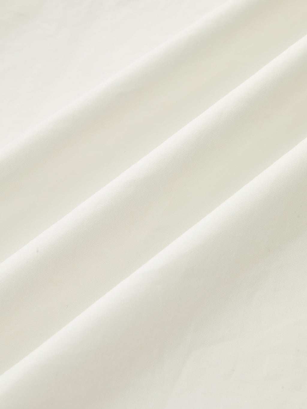 A strapless white maxi dress with ruched fabric and soft diagonal folds, minimalist design.