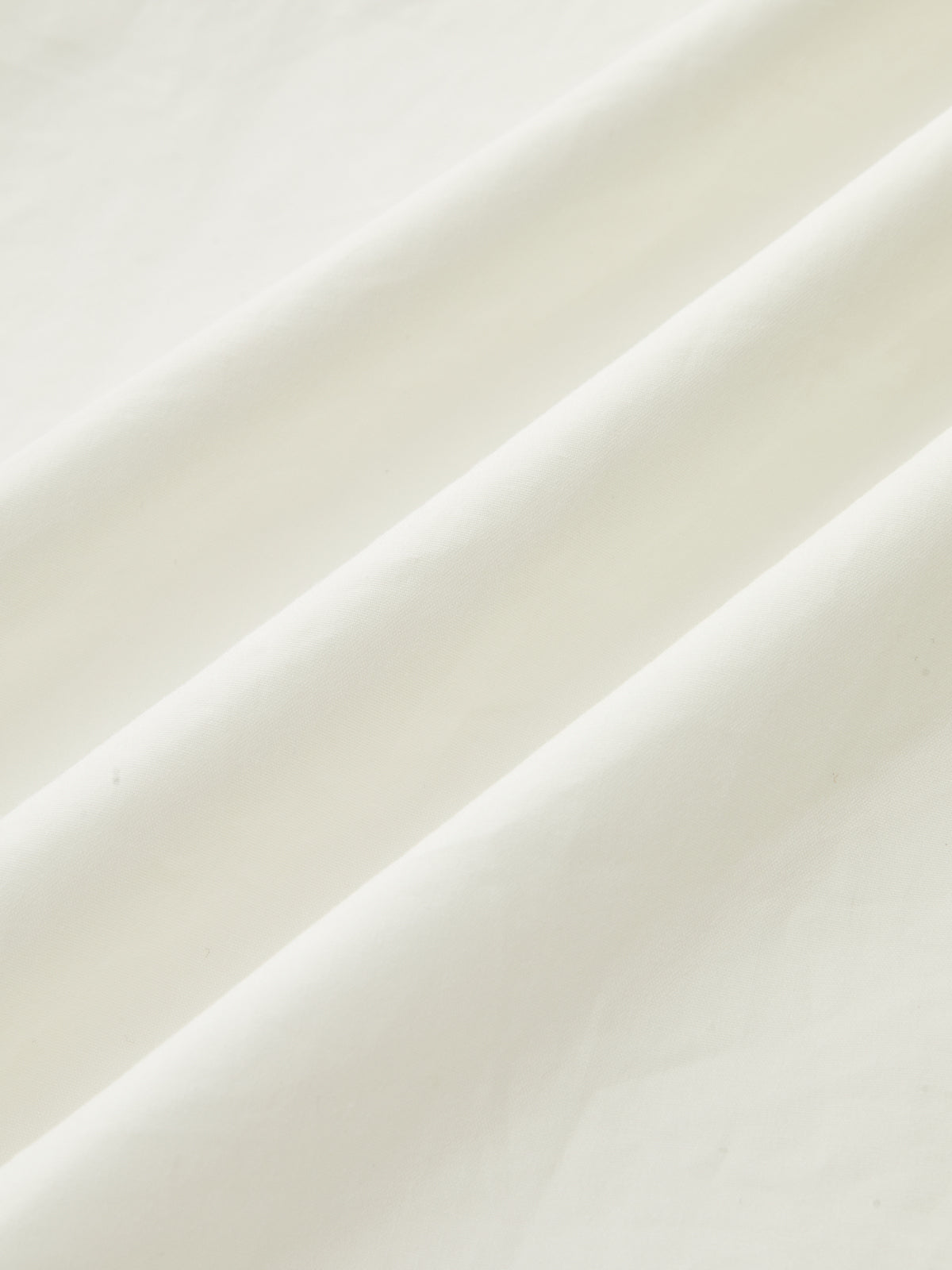 A strapless white maxi dress with ruched fabric and soft diagonal folds, minimalist design.