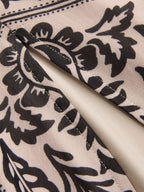 Beige flowy sleeveless maxi dress with black floral pattern, lined pocket, and neat stitching.