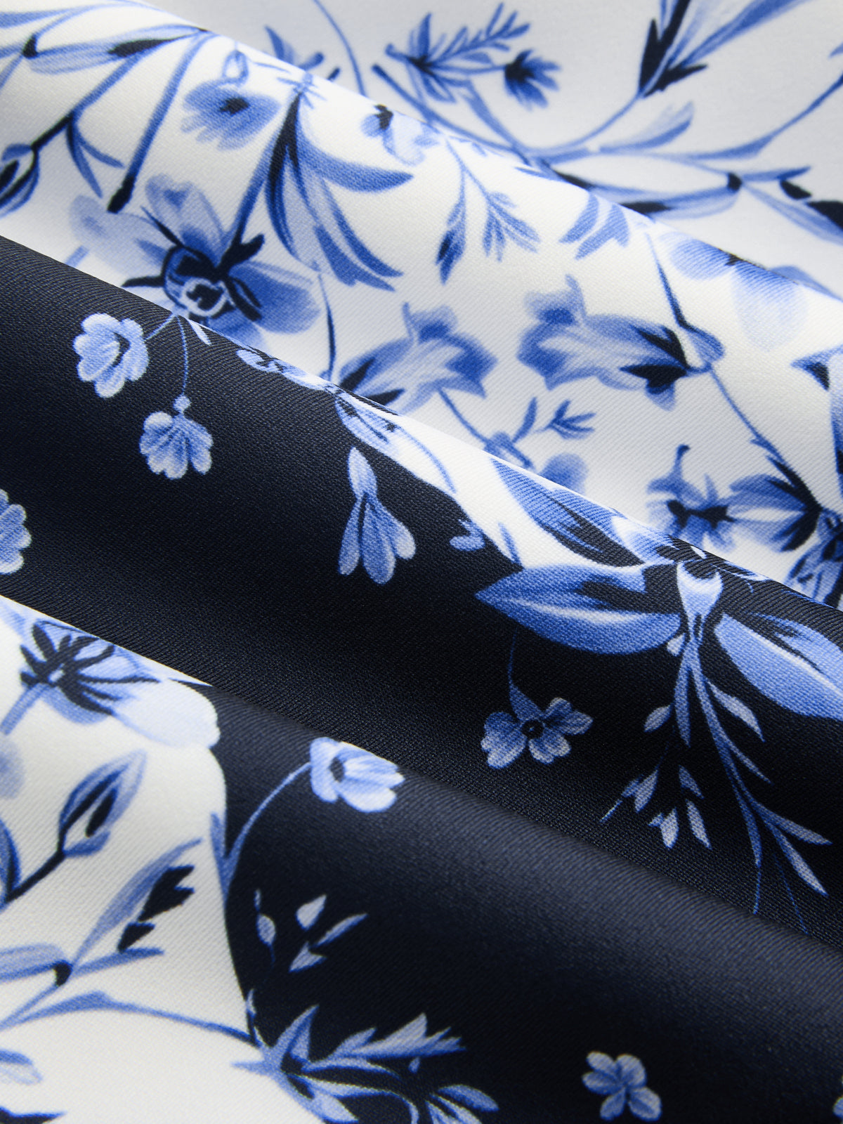Blue and white floral-patterned maxi dress with soft, shadowed folds and intricate detailing.