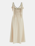 Sleeveless maxi dress with adjustable tie straps, smocked bodice, wavy trim, and flared skirt.